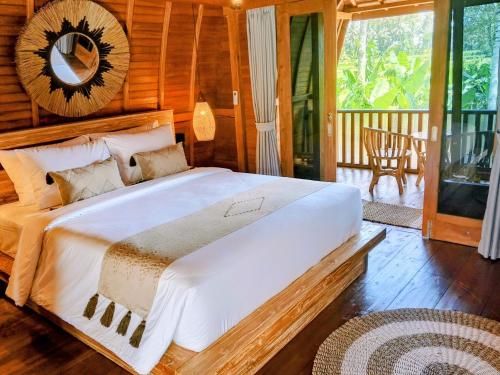 a bedroom with a large bed with a mirror on the wall at Bene Pertiwi Villa in Ubud