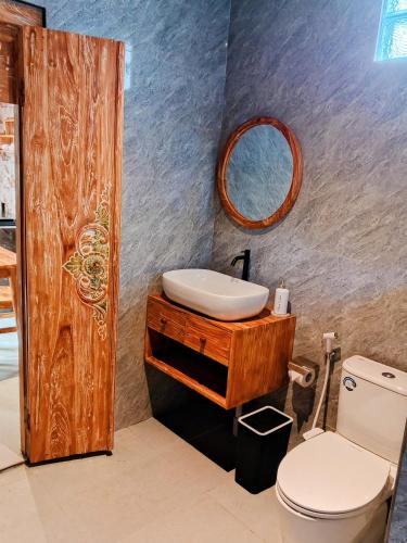a bathroom with a sink and a toilet and a mirror at Bene Pertiwi Villa in Ubud