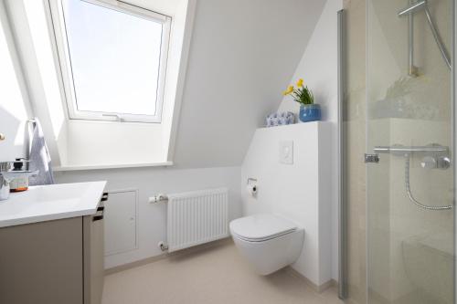 a white bathroom with a toilet and a window at Lønstrup Apartments, Havtorn in Lønstrup