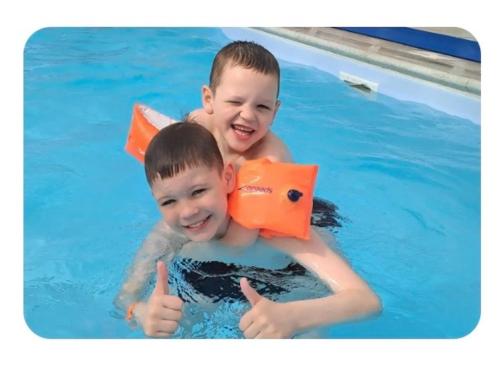 two young boys in a swimming pool giving thumbs up at 5 Minutes Walk From Beach , Fully Disabled,Pet Friendly Caravan With Hot Tub On Coastfields Holiday Village in Skegness