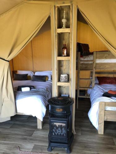 a tent with two beds and a stove in a room at Deer Barn Retreats in Hockworthy