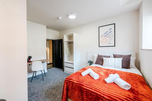 a bedroom with a bed with a orange blanket at Apex Studios by Derbnb in Derby
