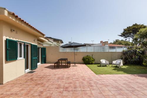 a patio with a table and chairs and an umbrella at Mindelo Beach House in Vila Chã