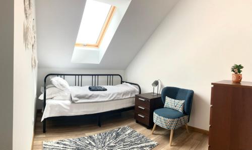 a bedroom with a bed and a chair at Szumny Apartment 13a in Brzozówka