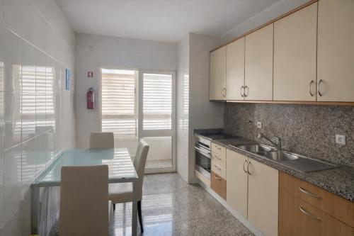 a kitchen with a table and a sink and cabinets at City World Apartment in Maia