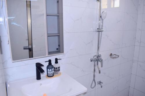 a bathroom with a shower with a mirror and a sink at DDS Homes Apartments in Dodoma