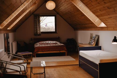 a attic room with two beds and a window at Domek gdzie śpią żurawie in Szymbark