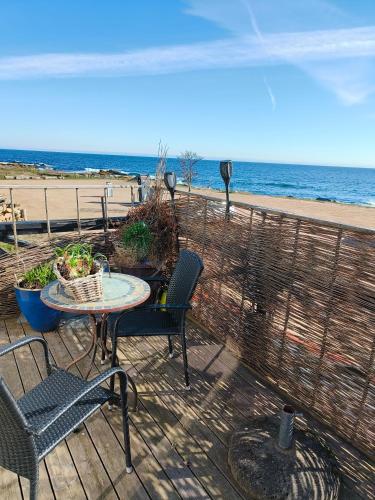 a patio with a table and chairs and the beach at Gruse 9 Svaneke in Svaneke