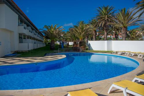 a swimming pool in a resort with palm trees at Hotel Torre Praia in Porto Santo