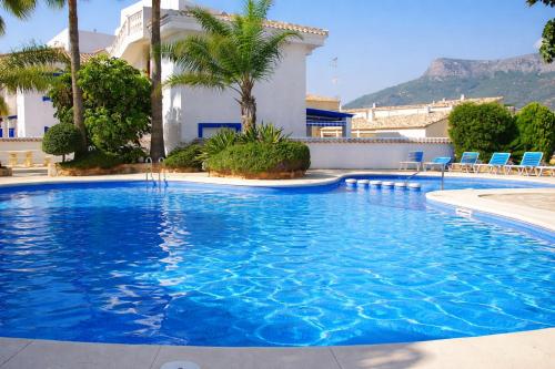 a large blue swimming pool with palm trees and a building at Casanova 20G Calpe - Ifach Holiday Homes in Calpe