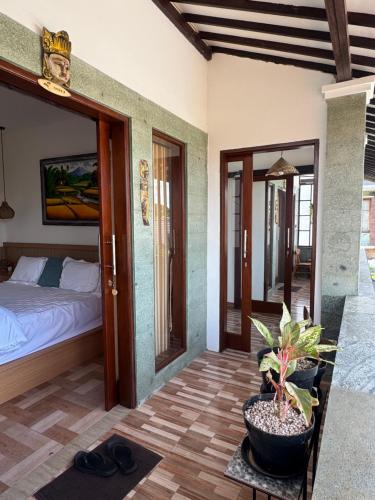 a bedroom with a bed and a table with a potted plant at Holi Saren Guest House in Nusa Dua
