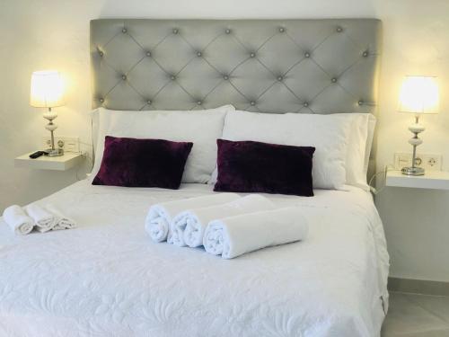 a white bed with towels on it with two lamps at La casa grande 2 in Carmona