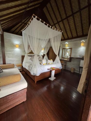 a bedroom with two beds and a canopy bed at The Jingga Villas in Nusa Lembongan