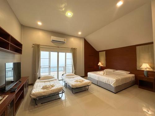 a hotel room with two beds and a television at Tsuya Hill Private Mountain View Villa, Chiang Rai in Mae Chan