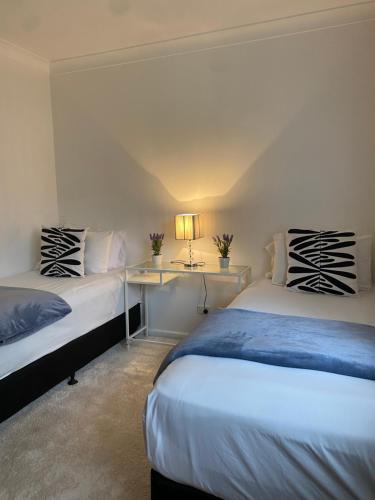 a bedroom with two beds and a table with a lamp at Family Haven Bradburry in Campbelltown South