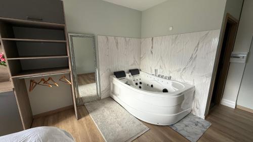 a bathroom with a bath tub and a mirror at La Rose du Lac Hôtel Appart' in Coucouron
