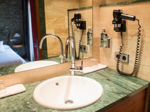 un baño con encimera con fregadero y 2 teléfonos en La Violeta HOTEL SPA & CHILL OUT, en Castelltersol