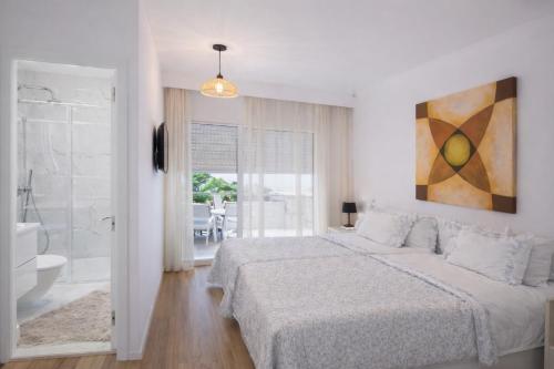 a white bedroom with a large bed and a bathroom at City World Apartment in Maia