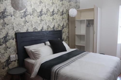 a bedroom with a bed with white pillows and floral wallpaper at Townside-Estate Room9 in Ladysmith