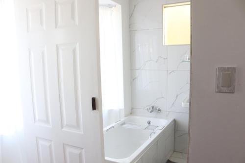 a white bathroom with a tub and a sink at Townside-Estate Room9 in Ladysmith