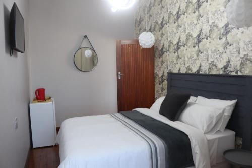 a bedroom with a bed with white sheets and a mirror at Townside-Estate Room9 in Ladysmith