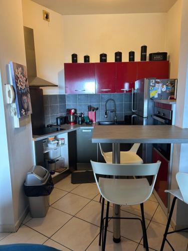 a kitchen with red cabinets and a table and chairs at LE MERYCE appt in Saint-Denis