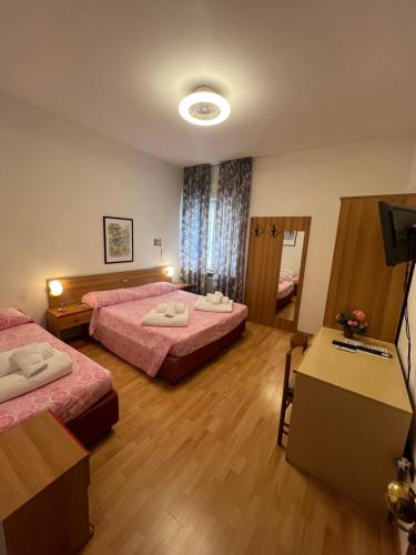 a hotel room with two beds and a television at Hotel Rialto in Riva del Garda