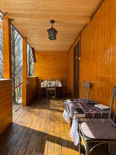 a porch of a wooden cabin with a bed and a table at Cabana lucia in Tarcău-Gheuca