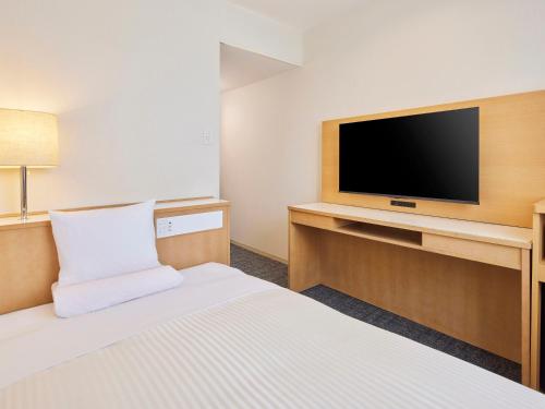 a hotel room with a bed and a flat screen tv at Matsuura City Hotel in Matsuura