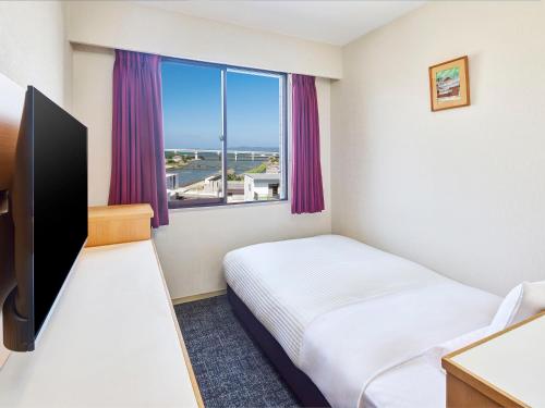 a hotel room with a bed and a window at Matsuura City Hotel in Matsuura