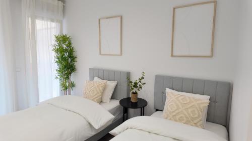 two beds with white sheets and pillows in a bedroom at The Eight Element Suites & Lofts in Madrid