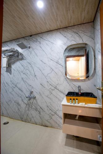 a bathroom with a sink and a mirror on a wall at Aarchh Royale in Noida