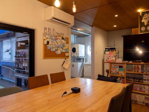 a room with a table in a library with a television at Guesthouse Nagonde in Kanazawa