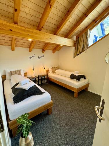 two beds in a room with a wooden ceiling at Louisa's Gallery - Whirlpool - Berge & Wandern - Abendruhe - familien- & gruppenfreundlich - 1h von Zürich in Alt Sankt Johann