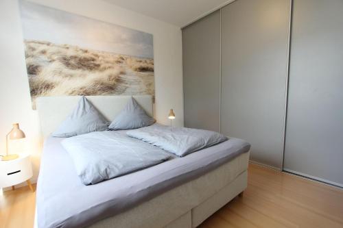 a bedroom with a bed with a painting on the wall at Langeoog entspannt in Langeoog