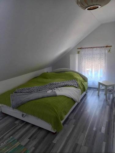 a bedroom with a bed with a green comforter and a table at Rsd-Tass vendéghàz in Tass
