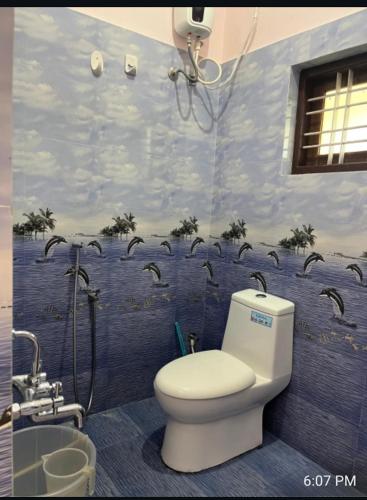 a bathroom with a toilet and a shower with birds on the wall at VallabhanAnnexHomestay in Varkala