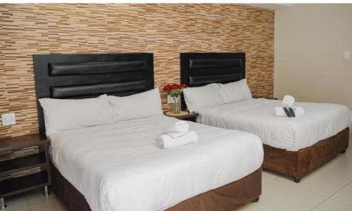 two beds in a hotel room with white sheets at J&J Paradise Guesthouse in Pietermaritzburg
