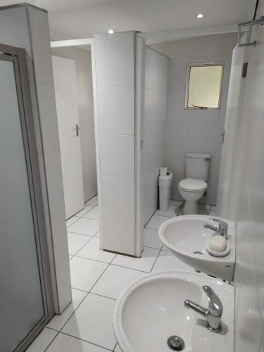 a white bathroom with a sink and a toilet at J&J Paradise Guesthouse in Pietermaritzburg