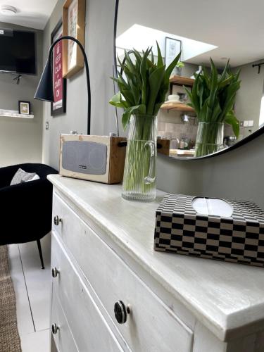 a vase of flowers on a dresser with a mirror at Studio 77 Cheltenham in Cheltenham