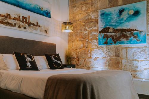 a bedroom with a bed with two pillows on it at Pjazza Suites Boutique Hotel by CX Collection in Siġġiewi