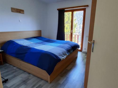 a bedroom with a bed with a blue comforter and a window at Casa Laetitia in Acquarossa