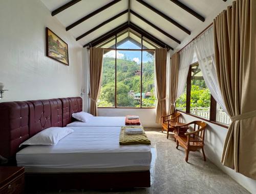 a bedroom with a bed and a large window at JungleRiverHouse & JungleRiverResort in Bukit Lawang