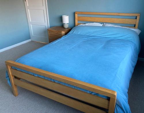 a bedroom with a large bed with a blue blanket at Cosy at Cumberland - Double room with shared bathroom in Dundonald