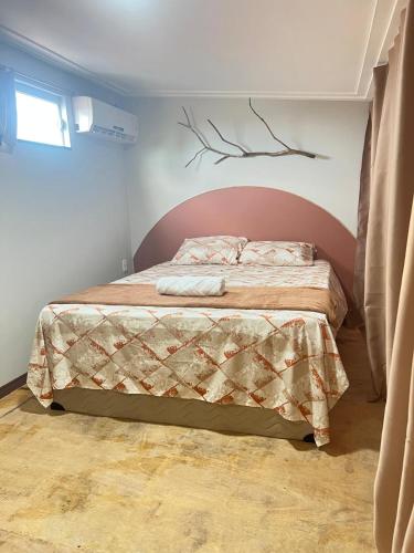 a bedroom with a bed in a room with a branch on the wall at Apt estiloso 01 in Paragominas