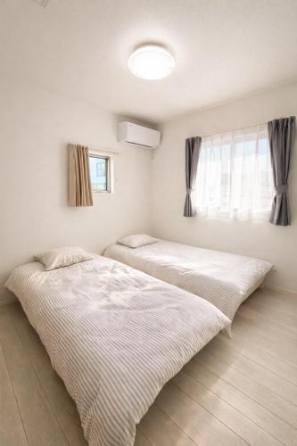 a bedroom with two beds and a window at 新築一棟貸切 民宿 夢 駐車場2台無料 コンビニ徒歩2分 市街地へ好アクセス in Matsuyama