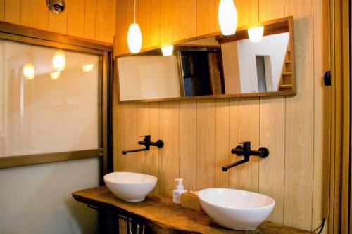 a bathroom with two white sinks on a wooden wall at ゲストハウス青い輝き in Marugame