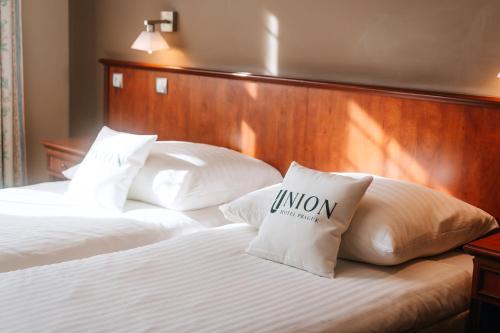 ein Bett mit weißen Kissen und einem hölzernen Kopfteil in der Unterkunft Union Hotel Prague in Prag