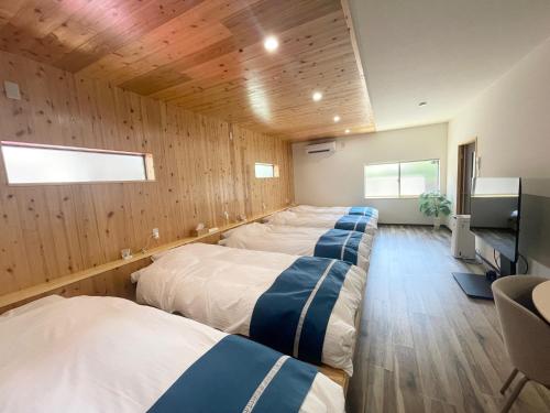 a row of beds in a room with wooden walls at Famille in Sumoto