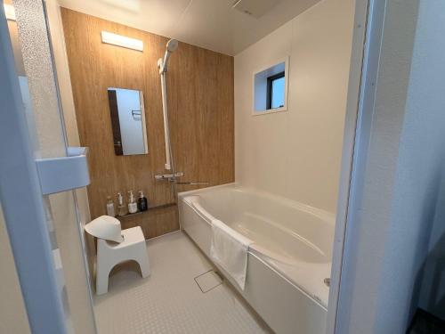 a bathroom with a white tub and a white stool at Famille in Sumoto